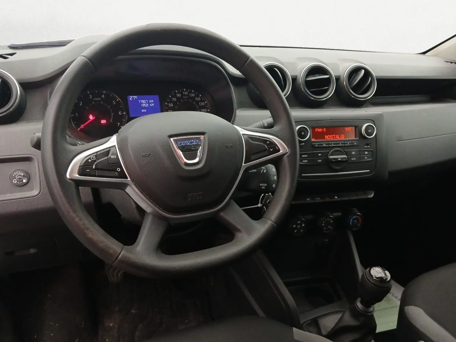 Vue intérieure centrée sur le volant noir du Dacia Duster 2021 avec tableau de bord et console radio allumée.