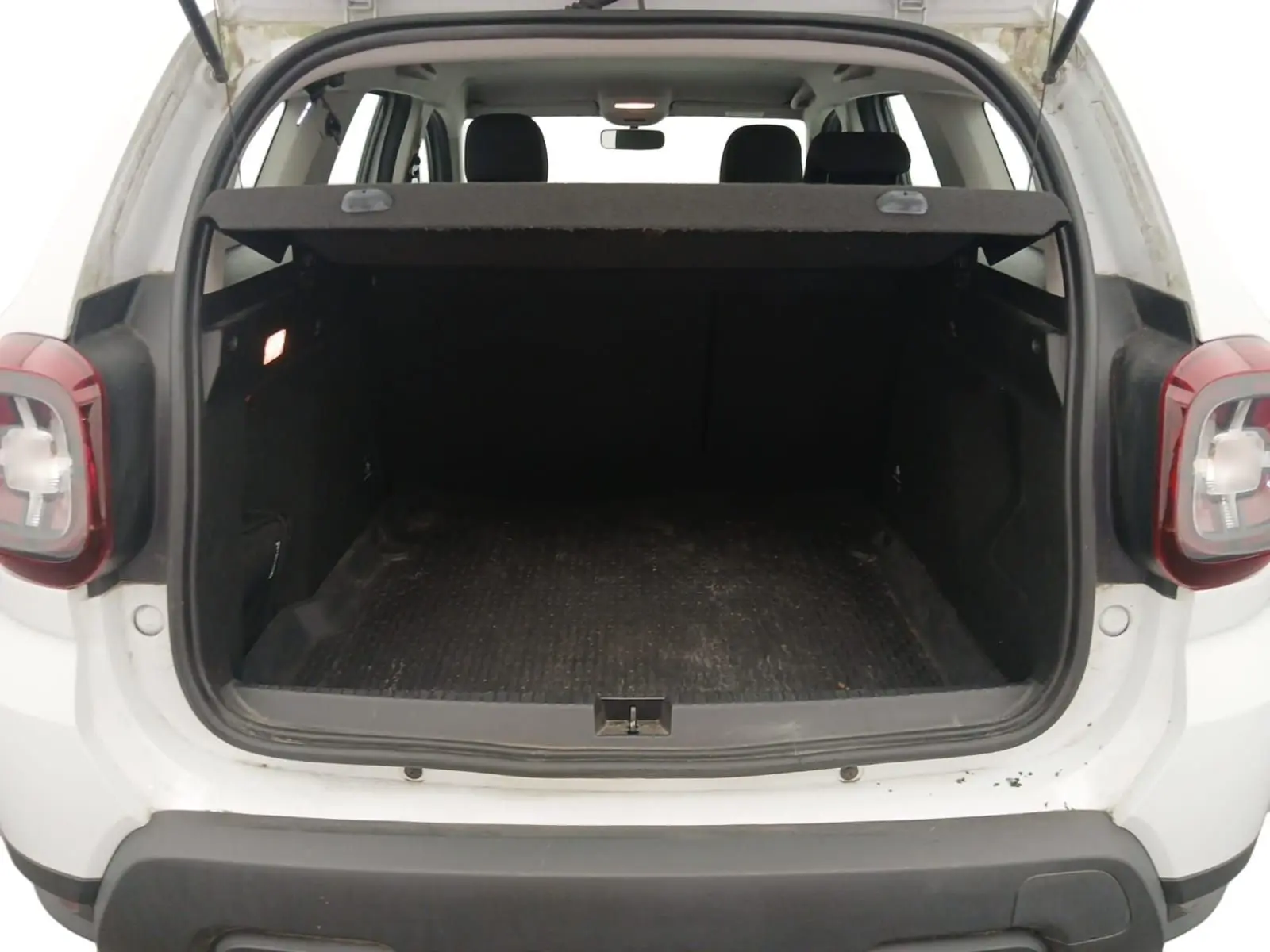 Coffre ouvert vu de l'arrière d'un Dacia Duster blanc 2021, montrant l'espace de chargement et les feux arrière.