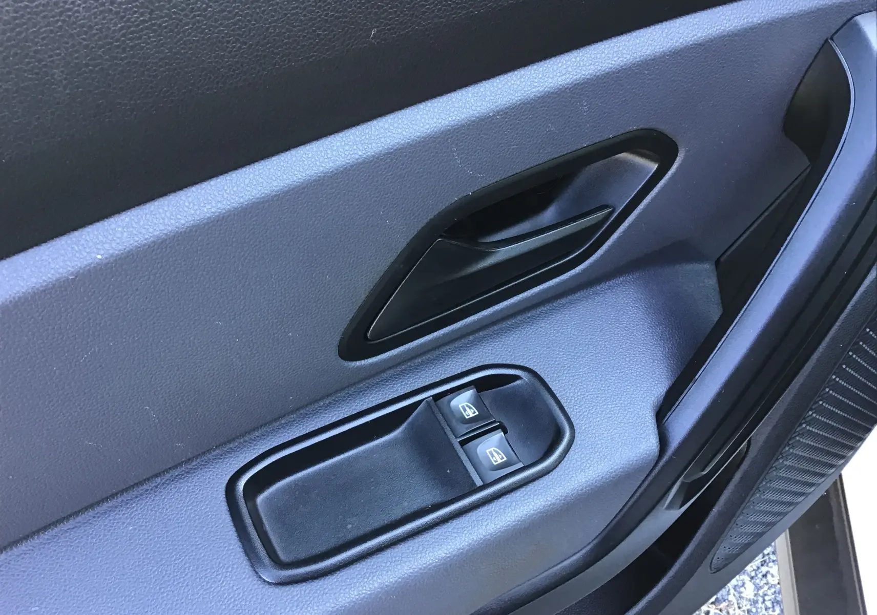 Gros plan sur la porte intérieure côté gauche du Dacia Duster blanc 2021, avec commandes de vitres électriques.