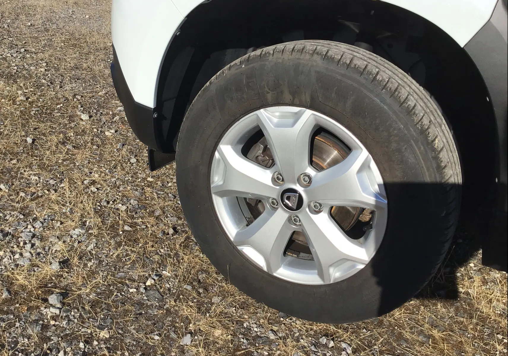 Gros plan sur la roue avant droite d'un Dacia Duster blanc 2021, avec jante alliage et pneu tout-terrain.