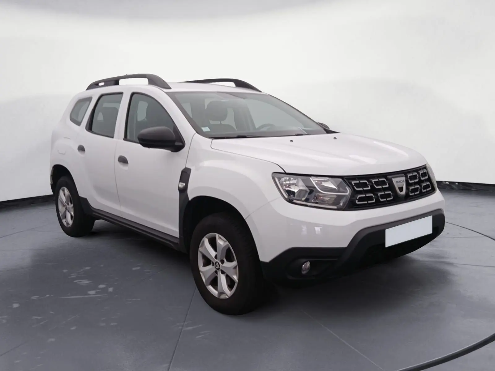 SUV Dacia Duster blanc 4x2 vue 3/4 avant droit avec calandre noire et barres de toit noires.