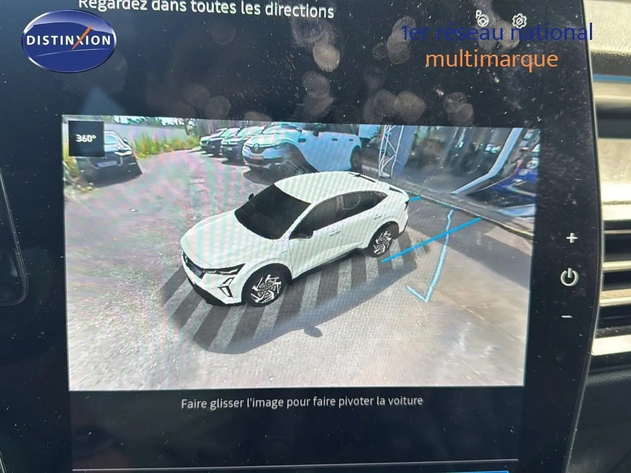 Vue 3/4 avant d'une Renault Rafale blanche 2024 affichée sur l'écran de contrôle avec indication de trajectoire de stationnement.