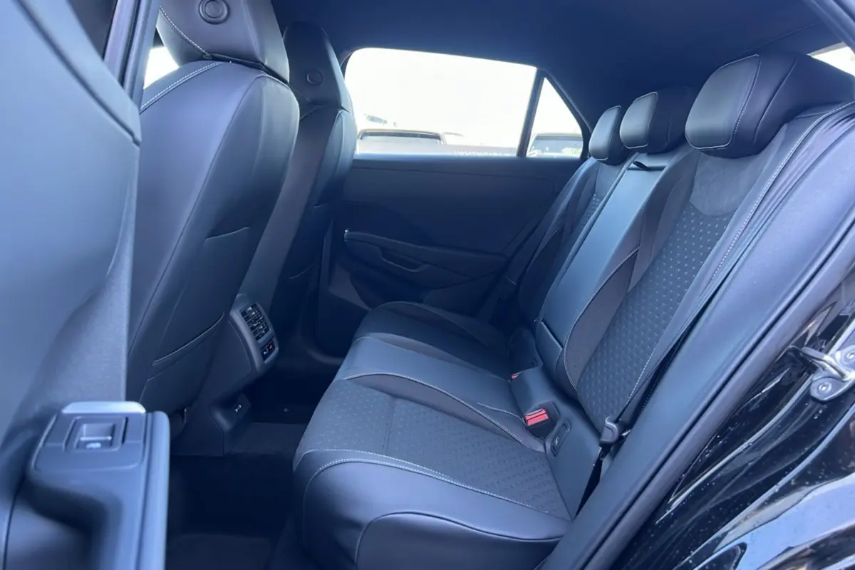 Vue intérieure arrière côté gauche du Volkswagen T-Roc noir ebène 2026, banquette tissu et cuir avec appuie-têtes.