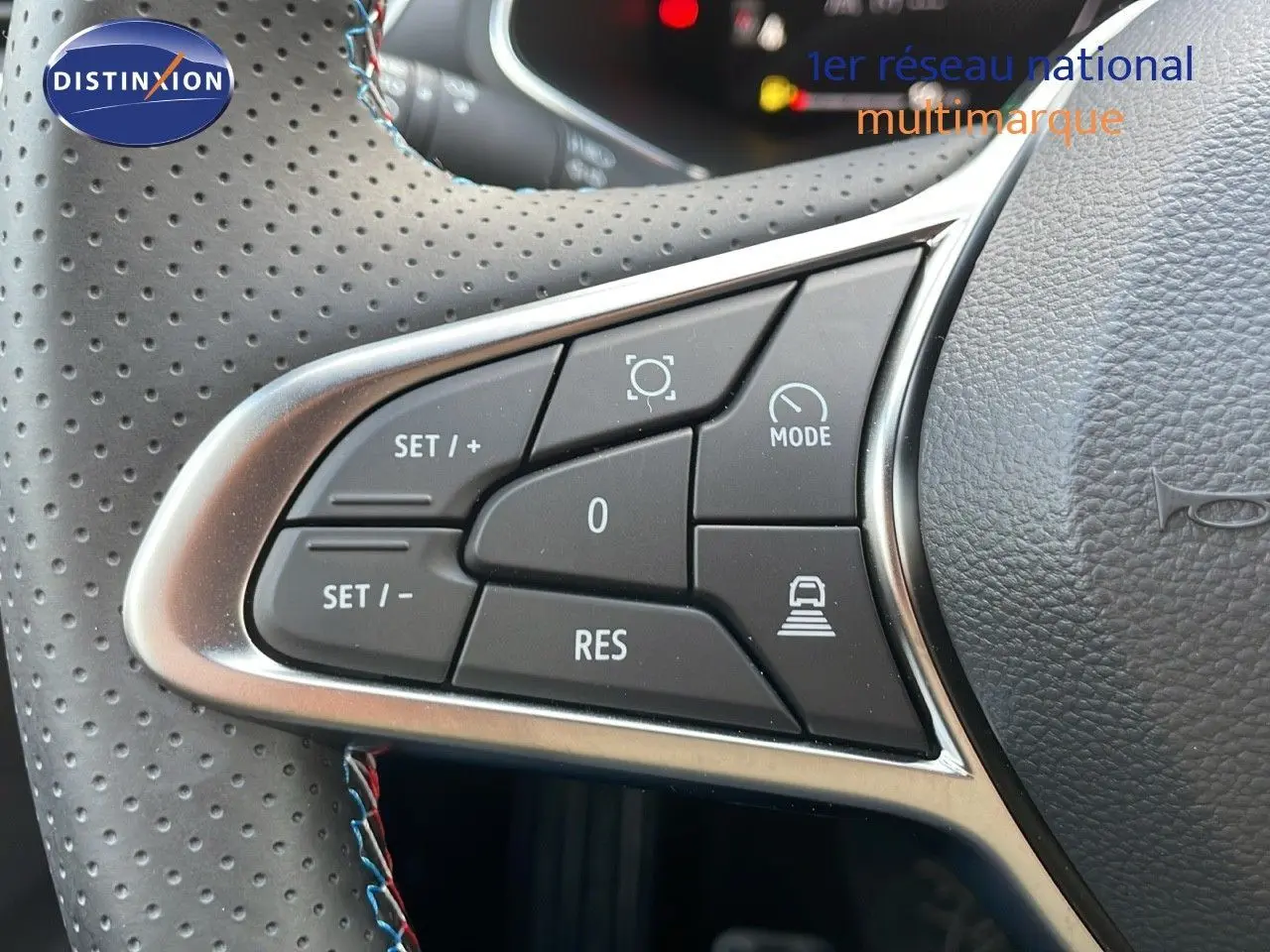 Gros plan sur les commandes au volant du Renault Captur E-Tech hybride 2025, cuir noir perforé avec surpiqûres tricolores.