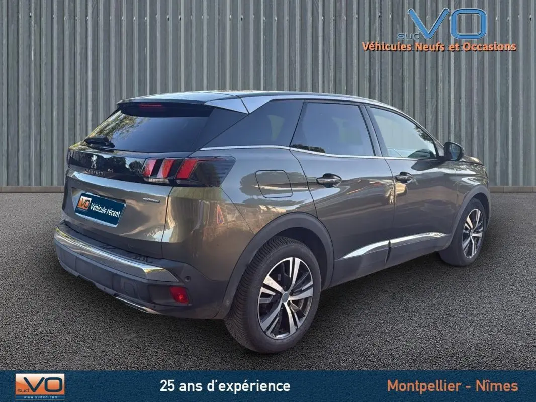 Peugeot 3008 gris foncé vue 3/4 arrière droit, jantes alliage 18 pouces et vitres teintées sur fond neutre.