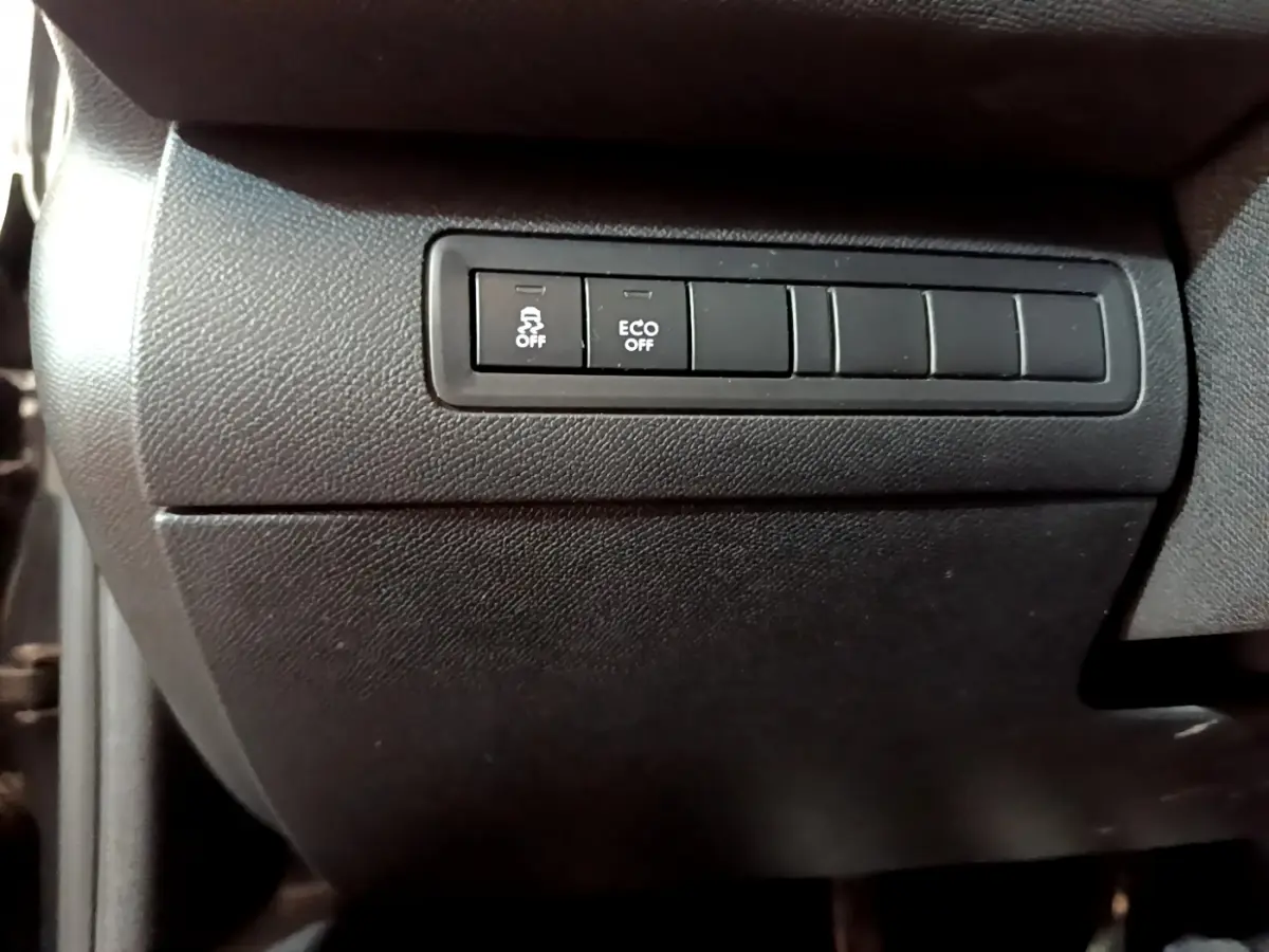 Boutons de commande du système antipatinage et mode ECO sur la console noire côté conducteur d'une Peugeot 308 gris foncé.