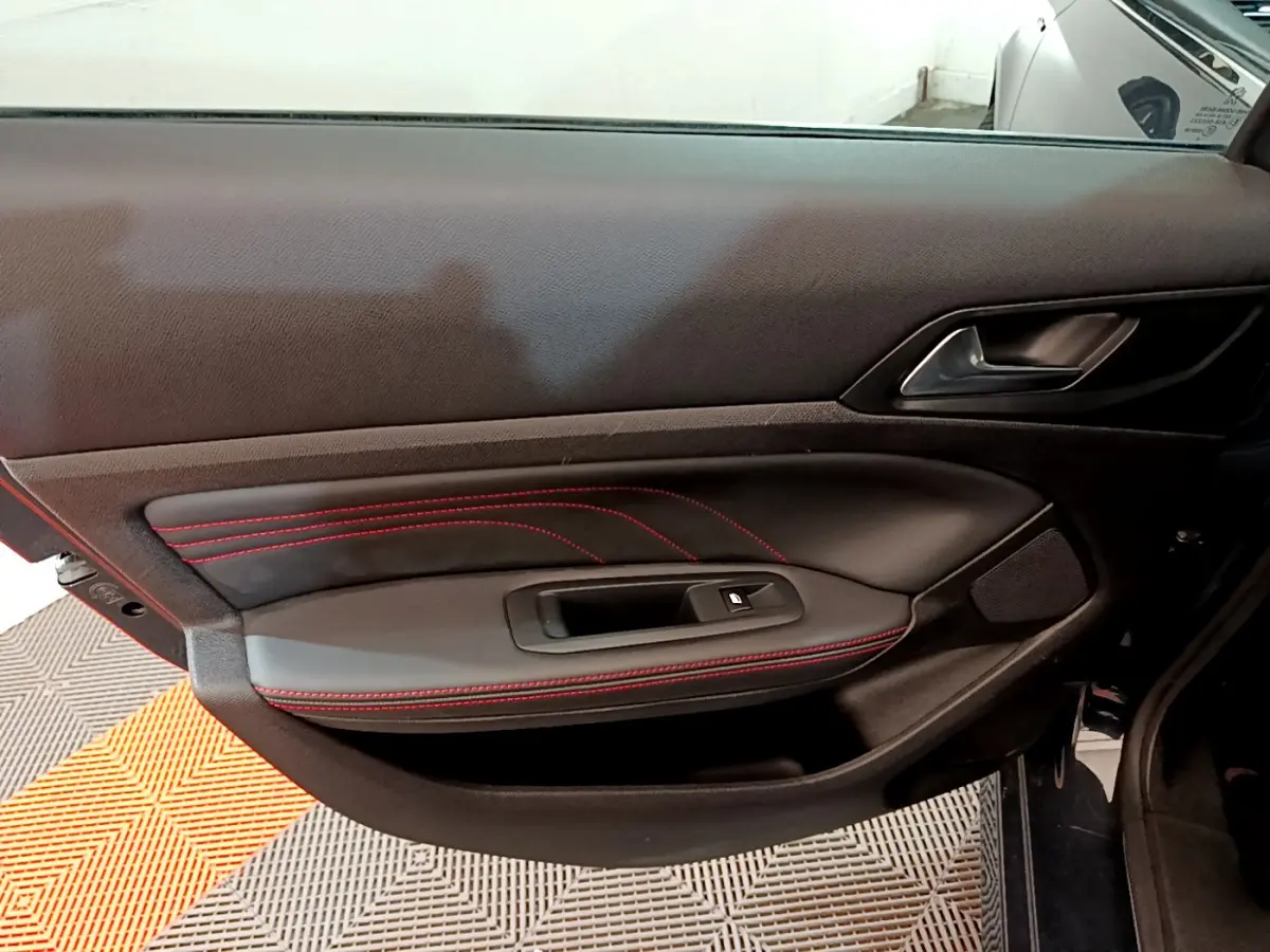 Gros plan sur la porte côté gauche de la Peugeot 308 GT Line 2016 avec surpiqûres rouges et poignée noire.
