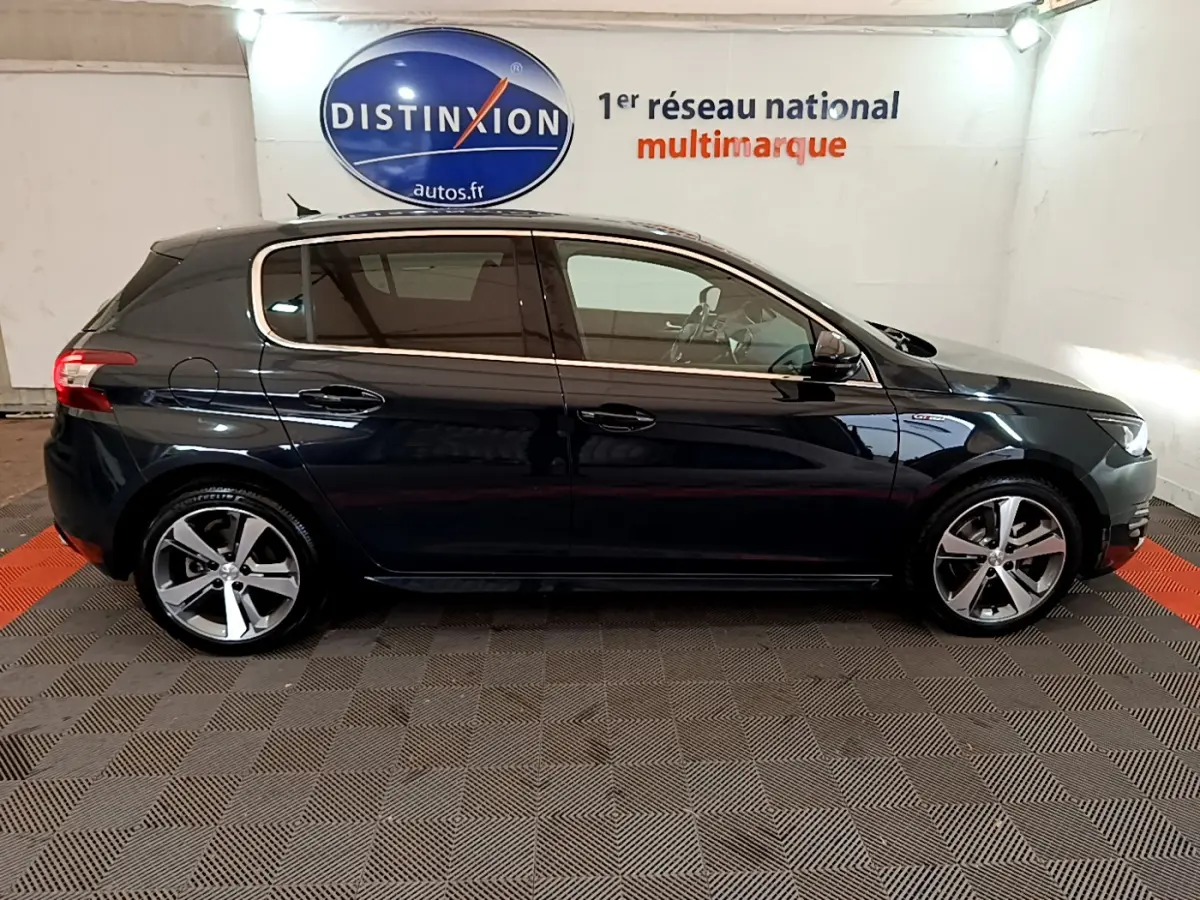 Profil côté gauche d'une Peugeot 308 gris foncé 2016 GT Line, avec jantes alliage et vitres teintées.