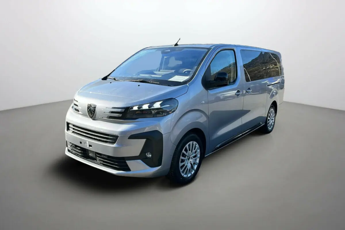 Vue 3/4 avant d'un Peugeot Traveller gris acier avec vitres surteintées et jantes alliage, sur fond neutre.