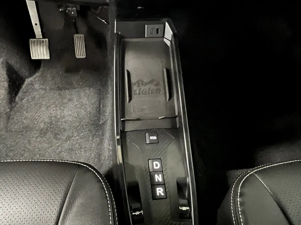 Vue rapprochée du levier de vitesses automatique noir et des pédales côté conducteur dans l’habitacle du Ligier JS50 rouge.