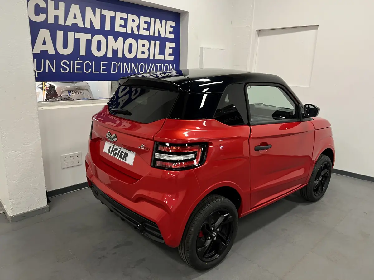 Vue 3/4 arrière droite d'une Ligier JS50 BEV 8KWH Elite rouge avec toit noir et jantes alu noires.