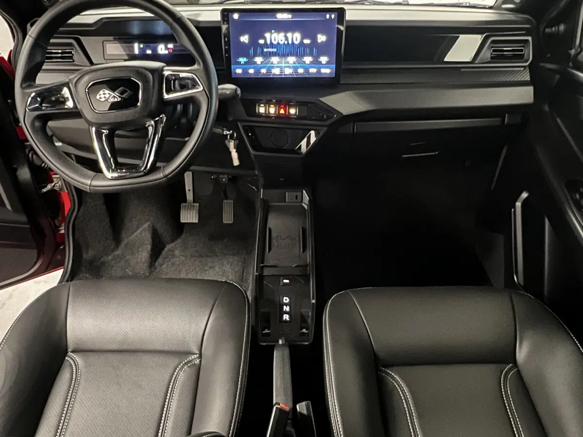 Vue intérieure avant de la LIGIER JS50 BEV 8KWH ELITE 2025, tableau de bord moderne avec écran tactile et sièges noirs.