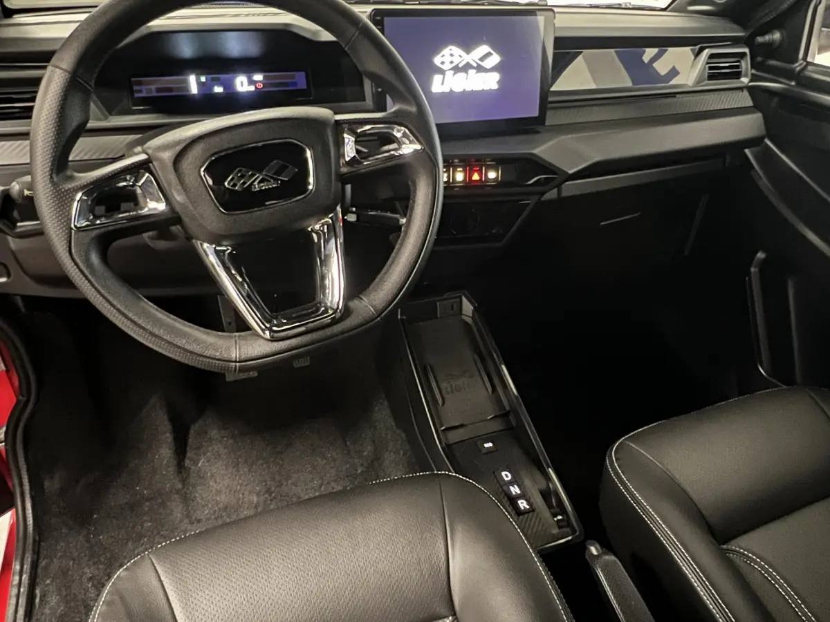 Vue intérieure du tableau de bord et volant du Ligier JS50 BEV 8KWH Elite avec écran tactile et sellerie noire.