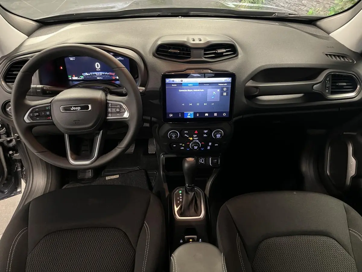 Intérieur Jeep Renegade 2024 vu de face, tableau de bord noir avec écran tactile central et volant multifonction.