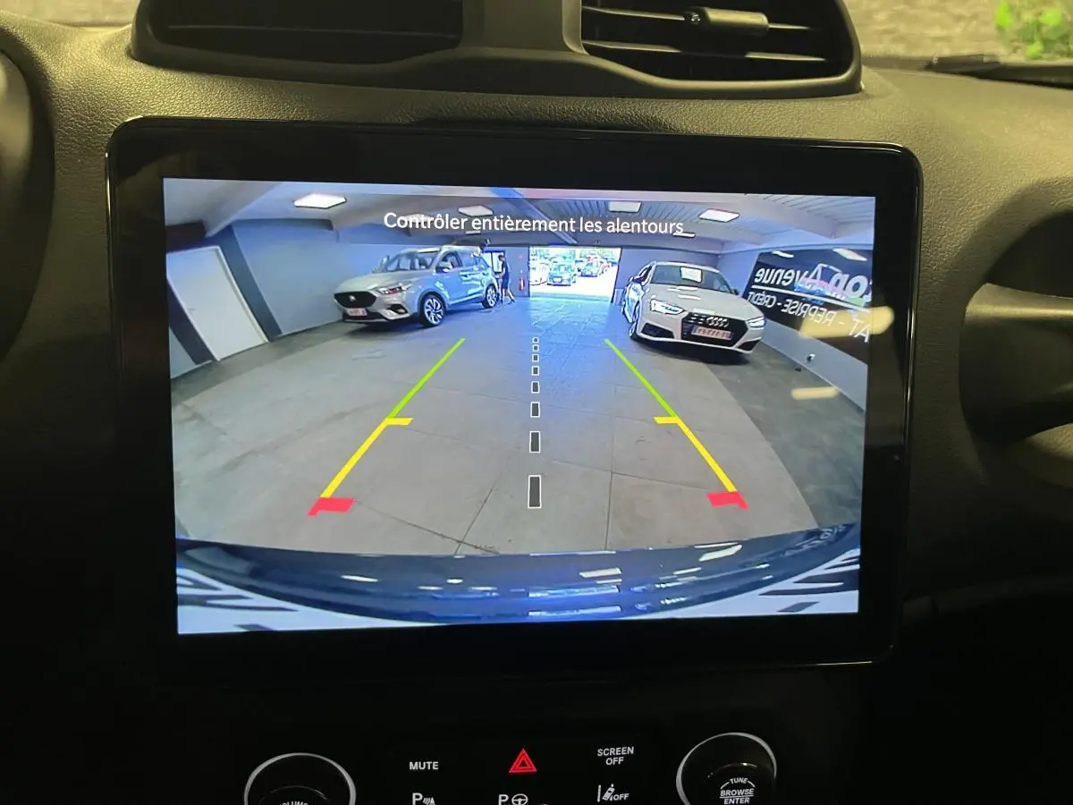 Vue arrière sur l'écran de caméra de recul montrant un Jeep Renegade gris stationné en intérieur avec marquages de guidage colorés.
