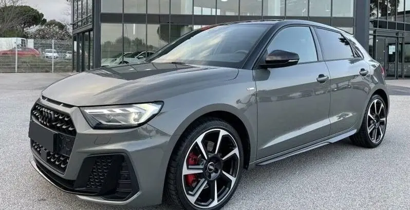Audi A1 Sportback 30 TFSI S-Line 2025 en gris Chronos avec toit noir, vue 3/4 avant côté gauche et jantes alu 18 pouces.