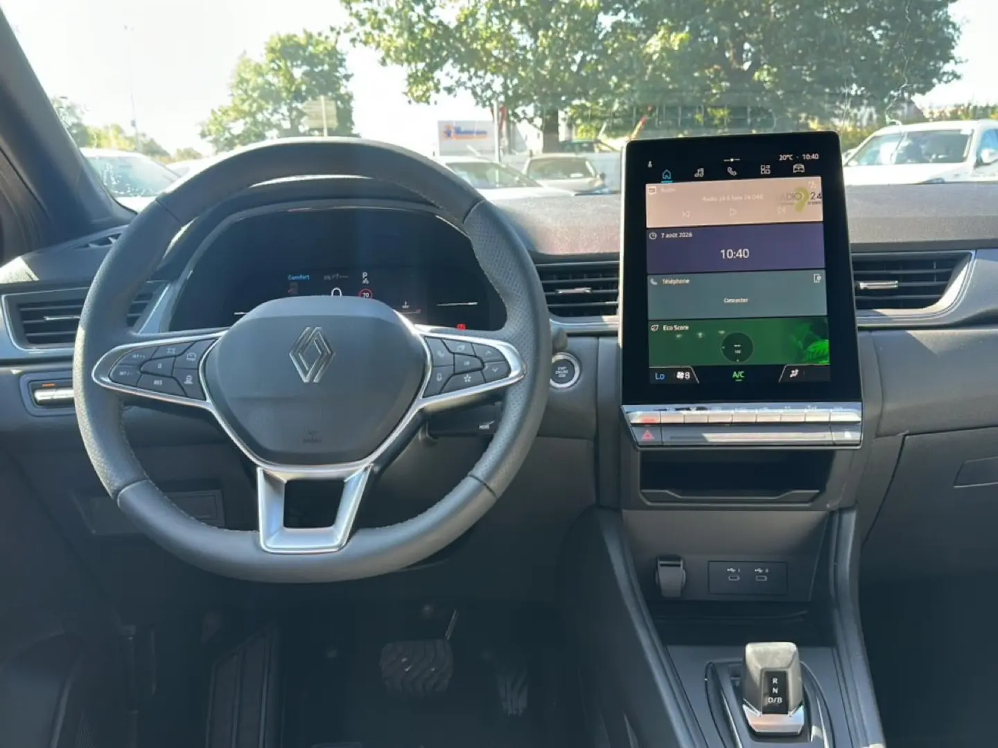 Vue intérieure frontale du tableau de bord du Renault Captur gris cassiopée, avec volant multifonction et écran tactile vertical.