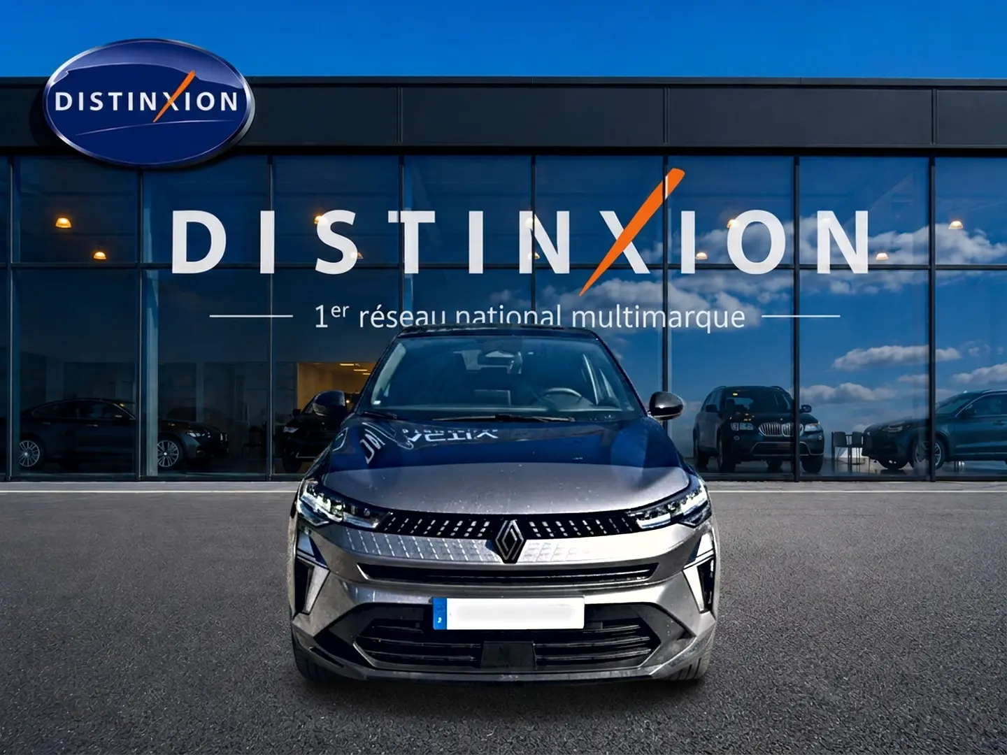 Vue avant d'un Renault Captur gris cassiopée 2026 garé devant une vitrine avec logo Distinxion.
