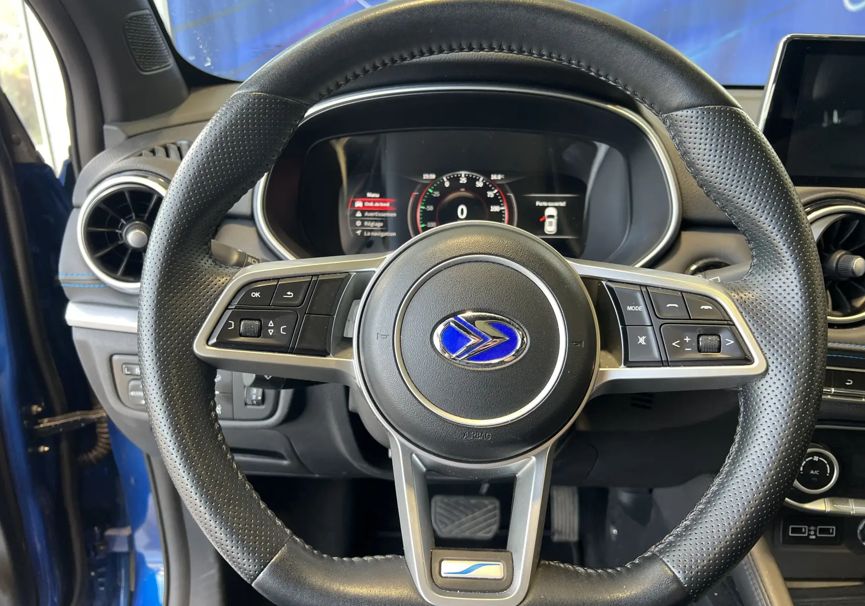 Vue centrée sur le volant noir perforé du SERES 3 Electric bleu astral avec tableau de bord digital allumé.