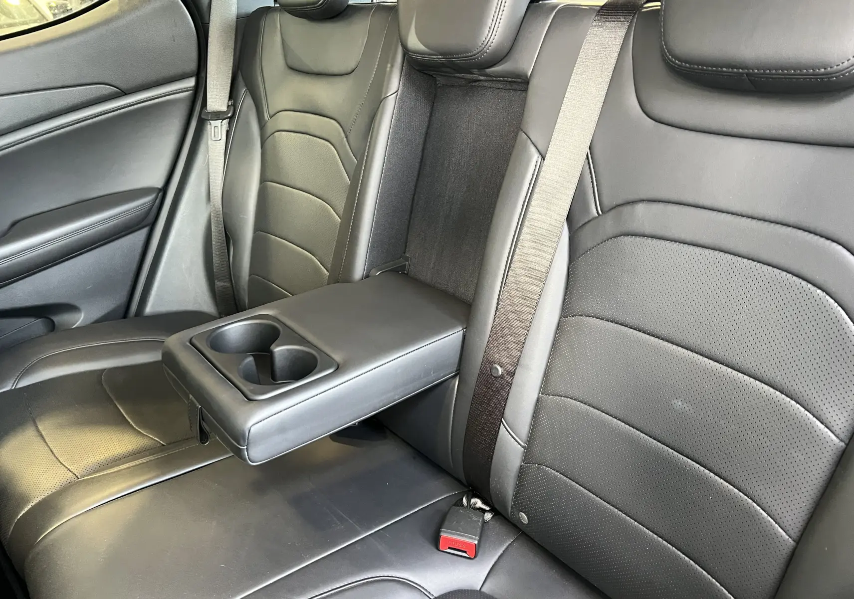 Vue rapprochée des sièges arrière noirs en cuir avec accoudoir central et porte-gobelets du SERES 3 Electric 2022.