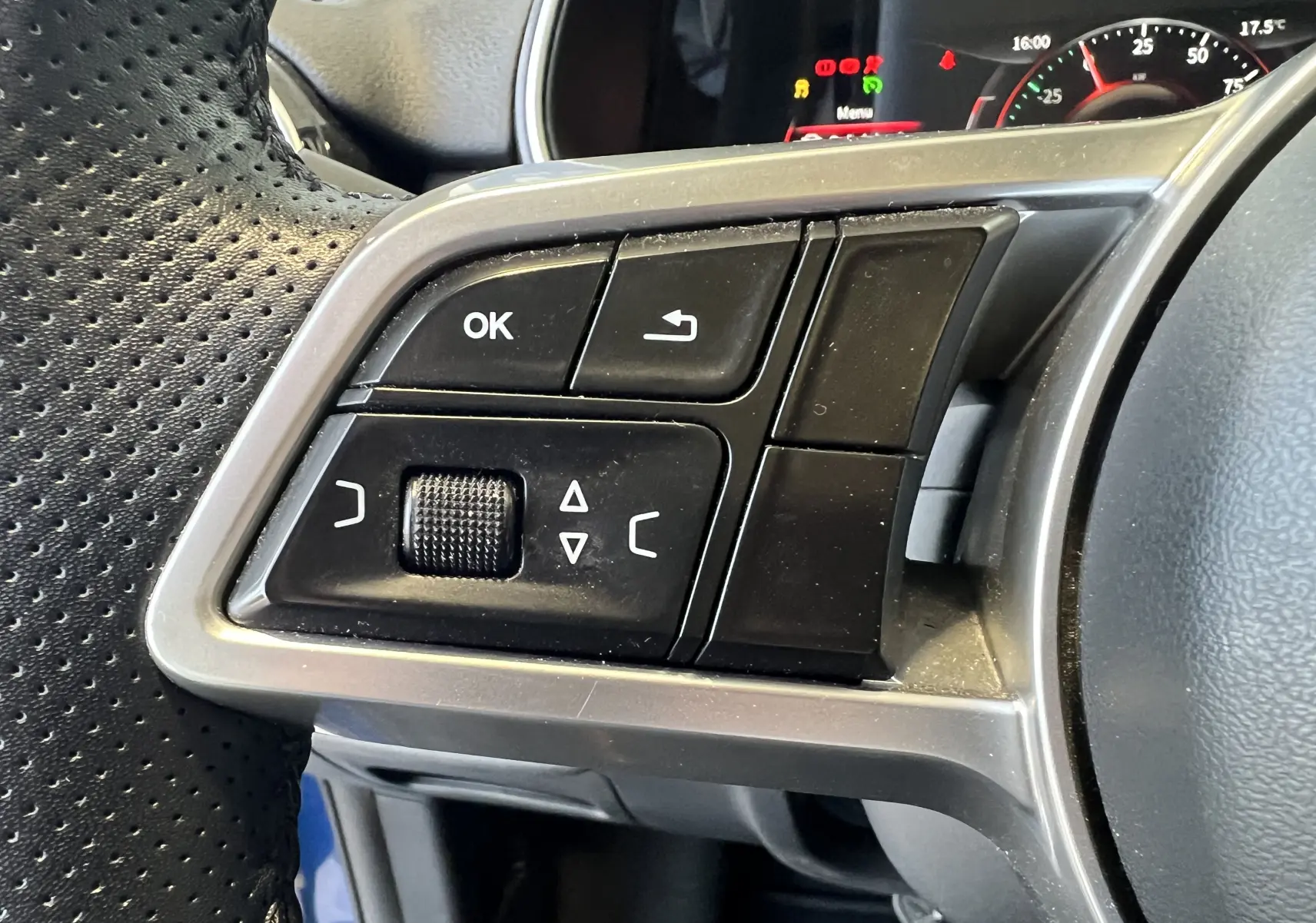 Gros plan sur les commandes gauche du volant perforé du SERES 3 Electric 163ch Luxe, tableau de bord partiellement visible.