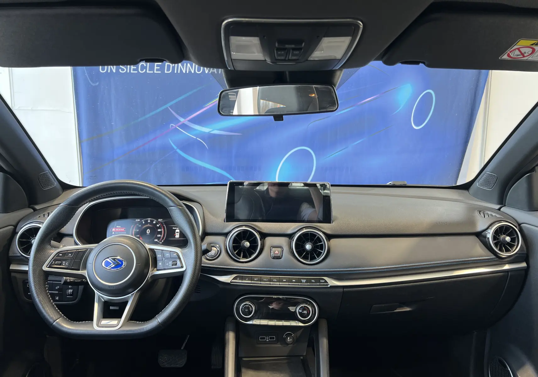 Vue intérieure frontale du tableau de bord noir du SERES 3 Electric 163ch Luxe avec écran tactile et volant multifonction.