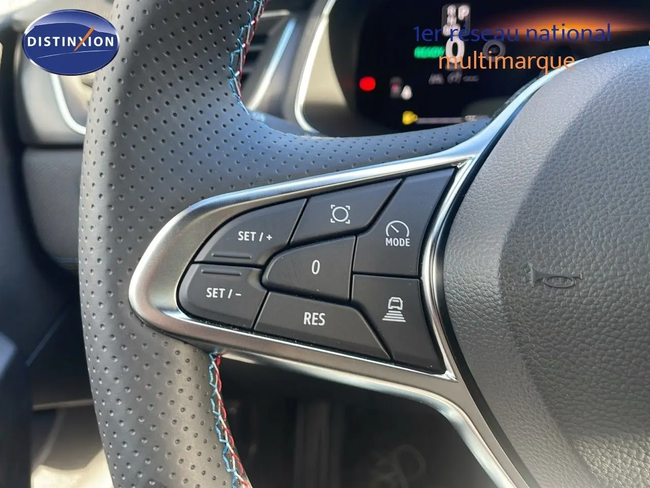Gros plan sur les commandes au volant en cuir perforé gris avec surpiqûres bleues du Renault Captur E-Tech hybride 2025.