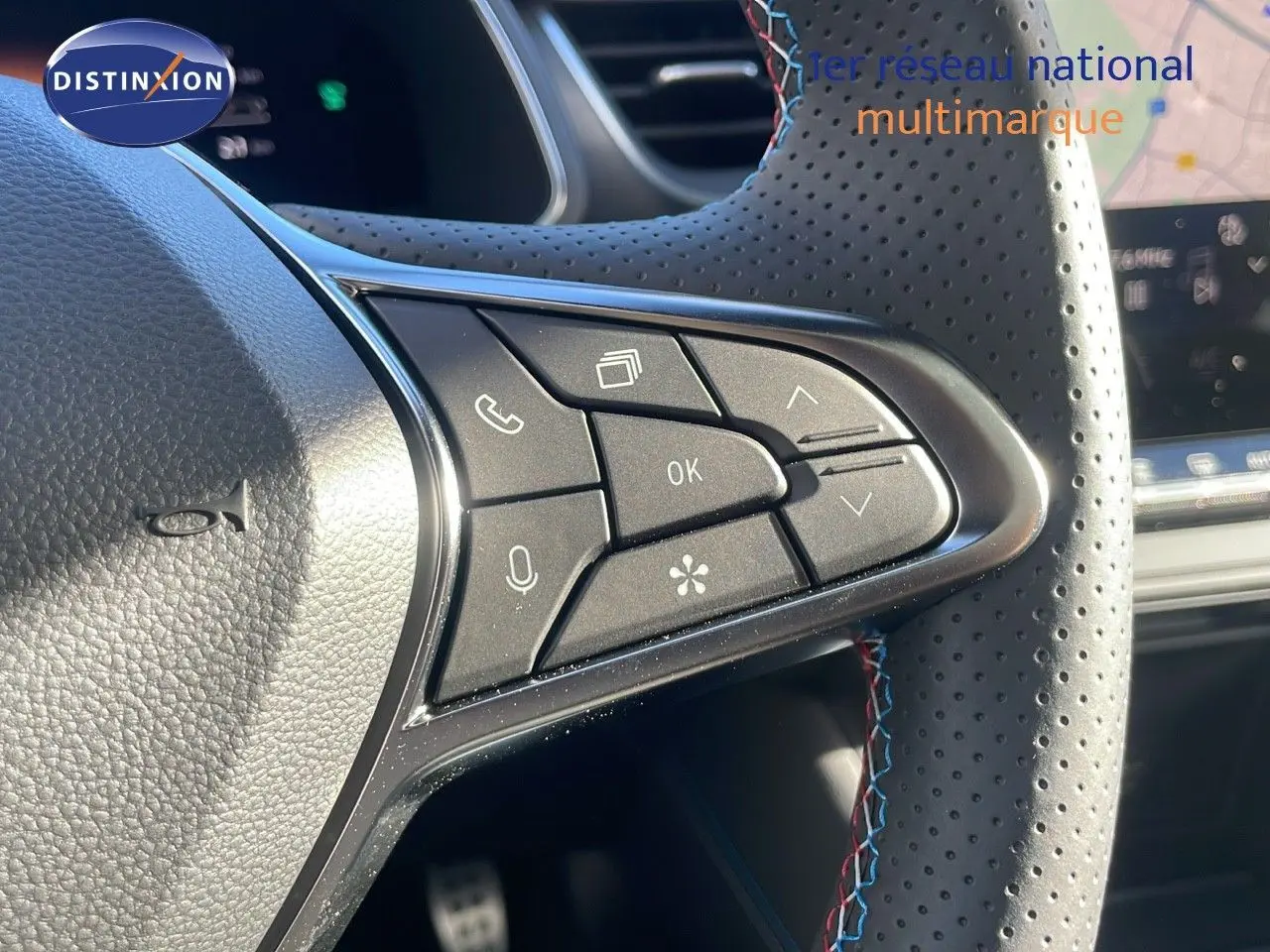 Gros plan sur les commandes au volant perforé avec surpiqûres tricolores du Renault Captur E-Tech gris Rafale 2025.