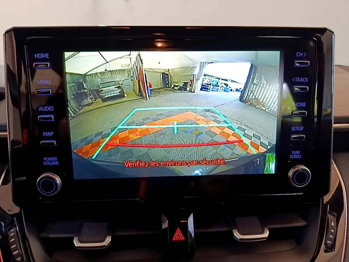 Écran tactile central montrant la caméra de recul avec guidage coloré sur Toyota Corolla noire hybride 2021.