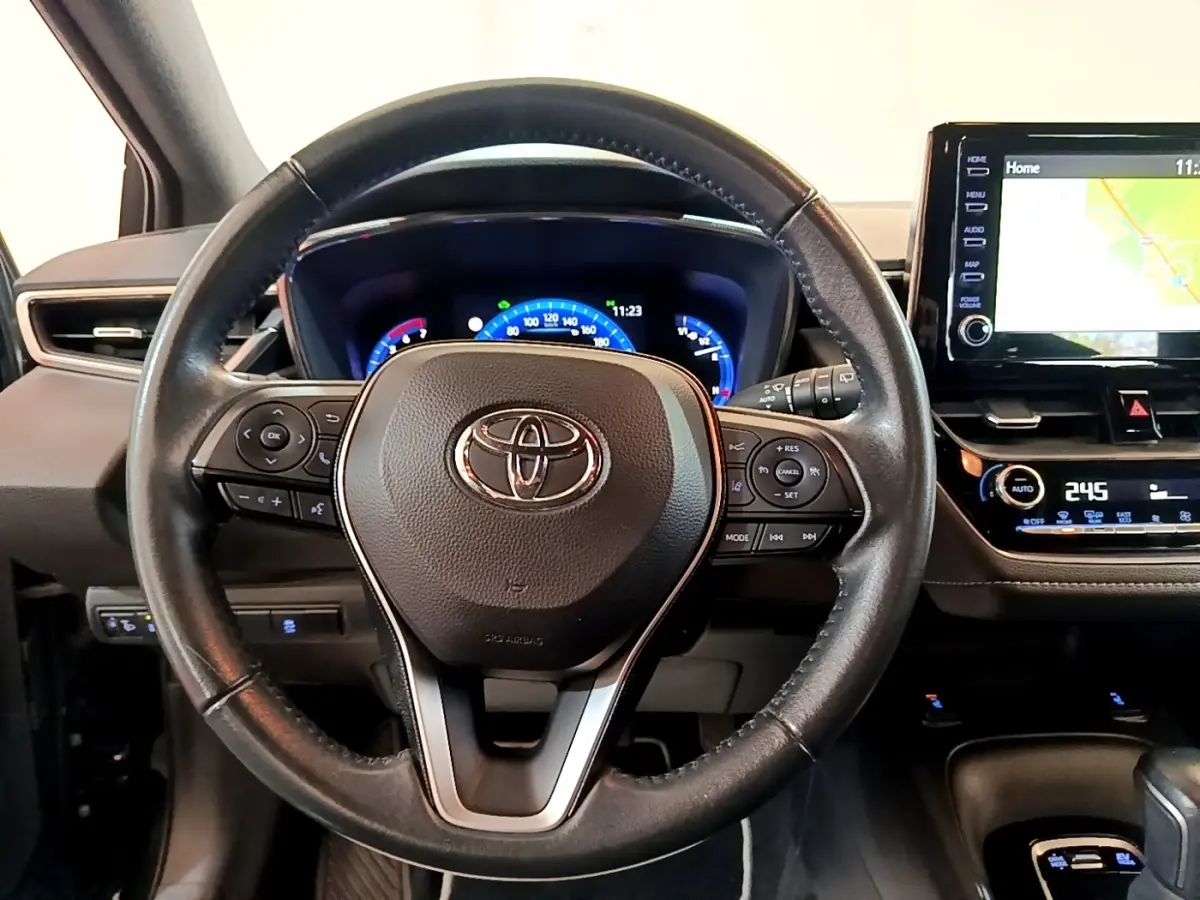Vue frontale du volant en cuir noir de la Toyota Corolla Hybride 2021 avec tableau de bord digital et écran tactile navigation.