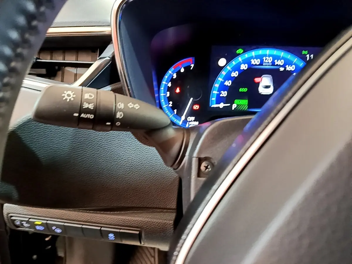 Gros plan sur le tableau de bord numérique bleu et noir de la Toyota Corolla hybride 2021, avec commandes d'éclairage visibles.