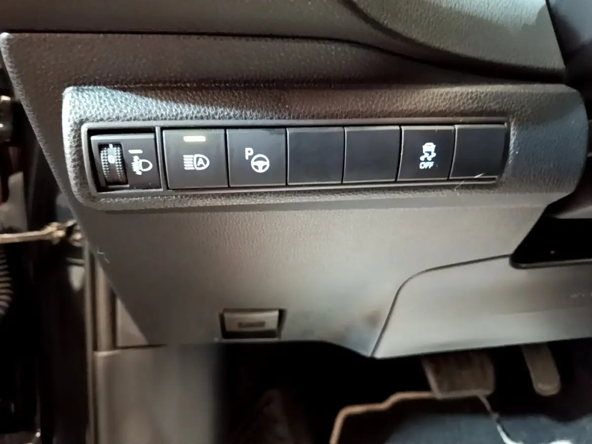 Gros plan sur les commandes noires sous le tableau de bord de la Toyota Corolla hybride 2021, côté conducteur.