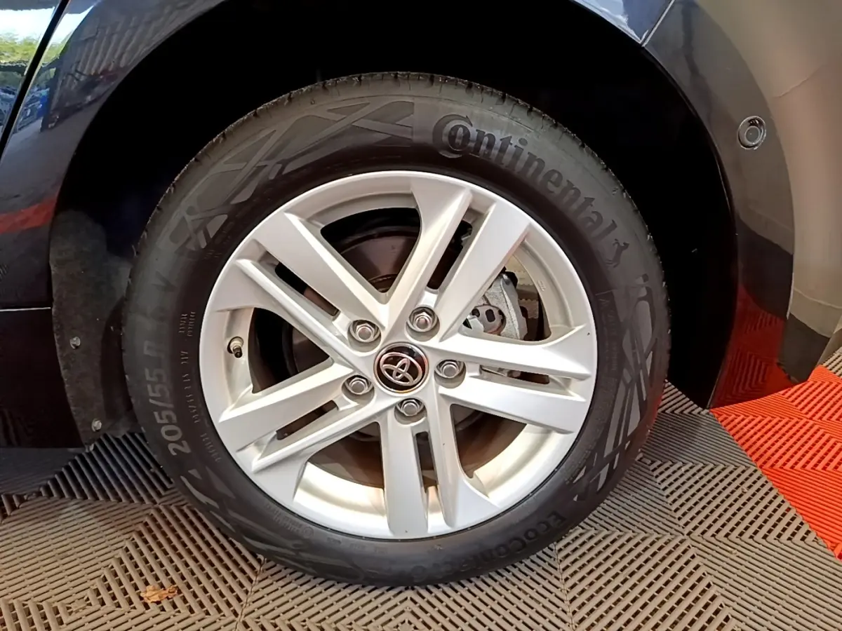 Gros plan sur la roue avant droite noire d'une Toyota Corolla hybride avec jante argentée et pneu Continental.