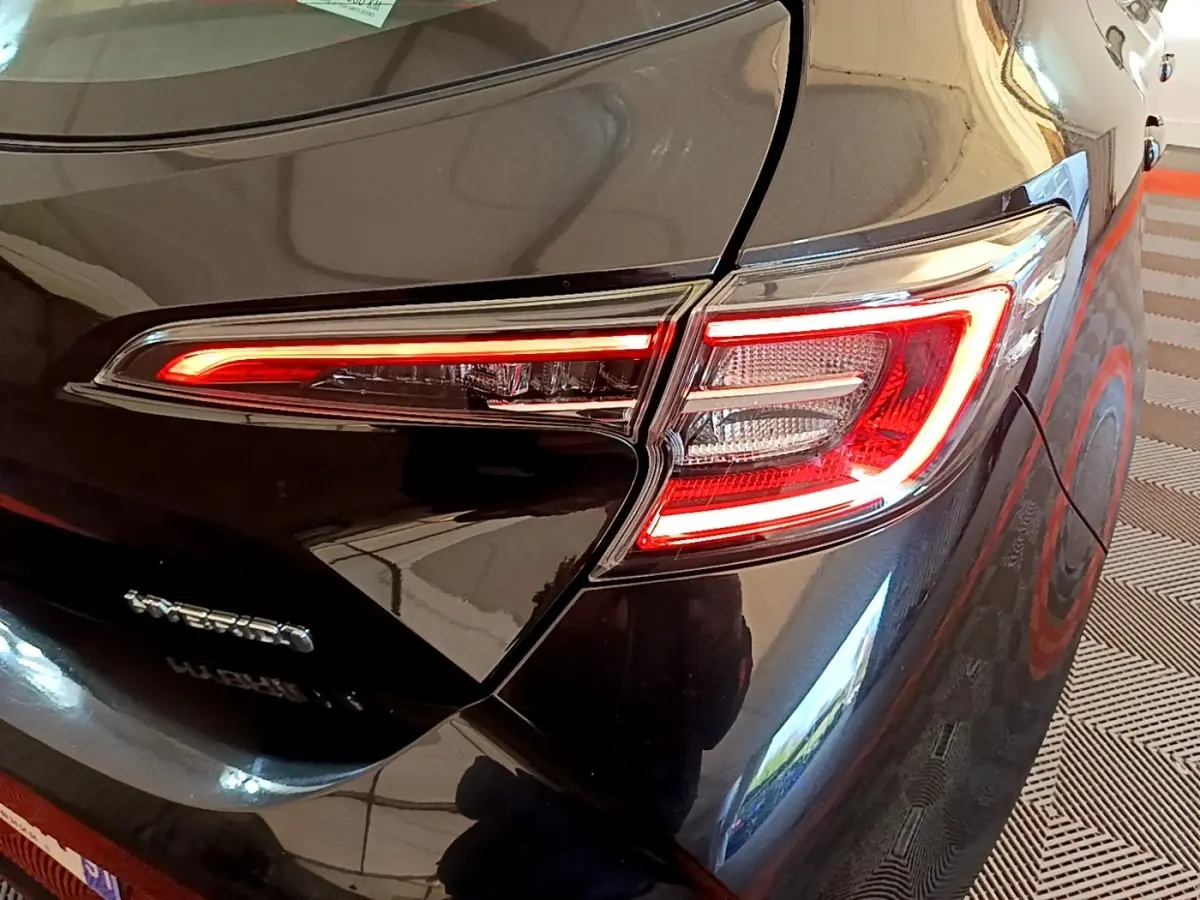 Feu arrière droit allumé sur une Toyota Corolla hybride noire, vue rapprochée du coin arrière du véhicule.