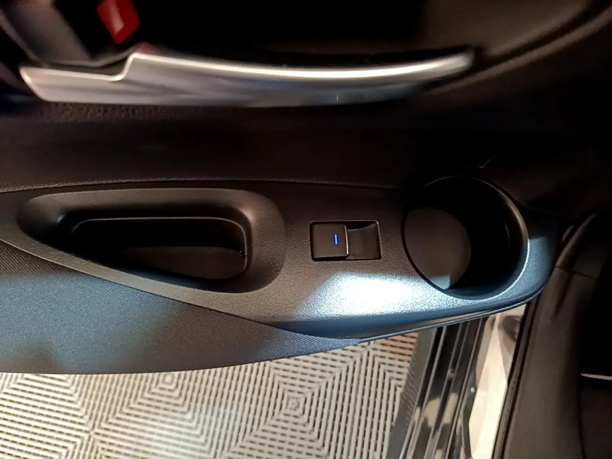 Poignée de porte intérieure côté conducteur noire avec bouton de verrouillage éclairé sur Toyota Corolla hybride 2021.