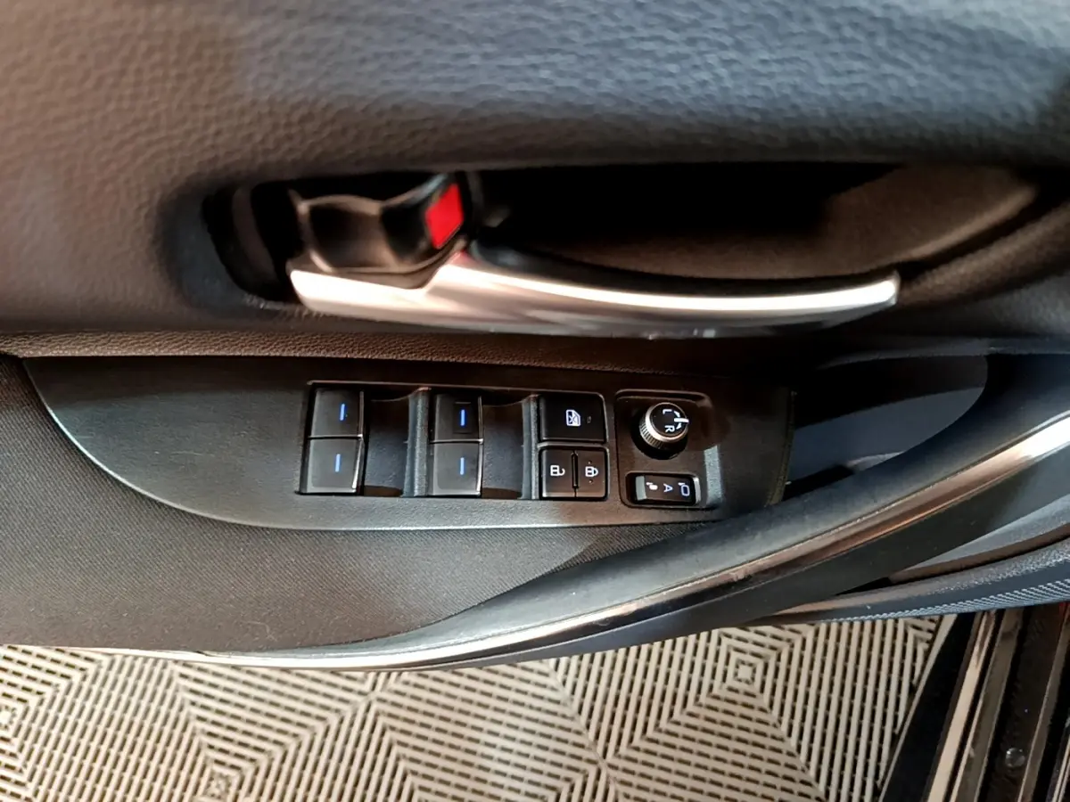 Gros plan sur la commande des vitres et rétroviseurs côté conducteur d'une Toyota Corolla noire hybride 2021.