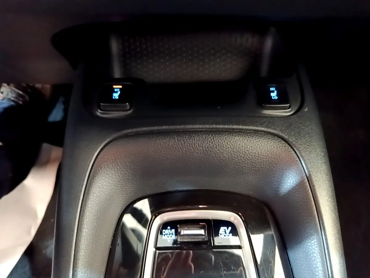 Gros plan sur la console centrale noire de la Toyota Corolla hybride, montrant les boutons Drive Mode et EV Mode.