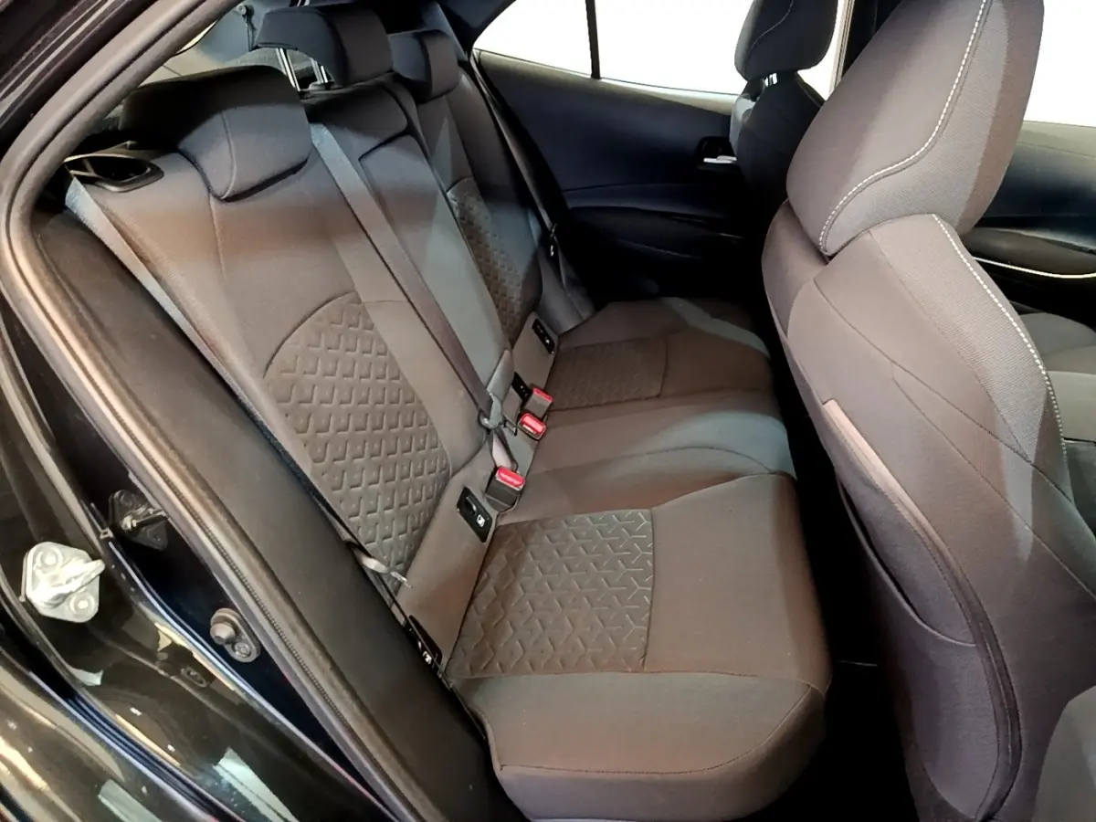 Vue intérieure côté gauche des sièges arrière noirs en tissu de la Toyota Corolla hybride 2021 avec motifs géométriques.