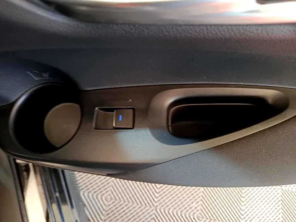 Poignée intérieure de porte côté gauche avec bouton de verrouillage, sur Toyota Corolla hybride noire 2021.