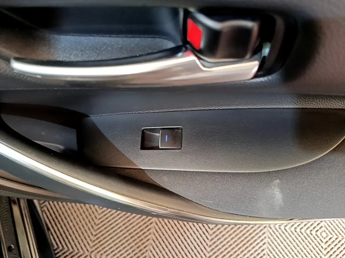 Gros plan sur la poignée intérieure et bouton de verrouillage de la porte côté gauche d'une Toyota Corolla noire hybride 2021.