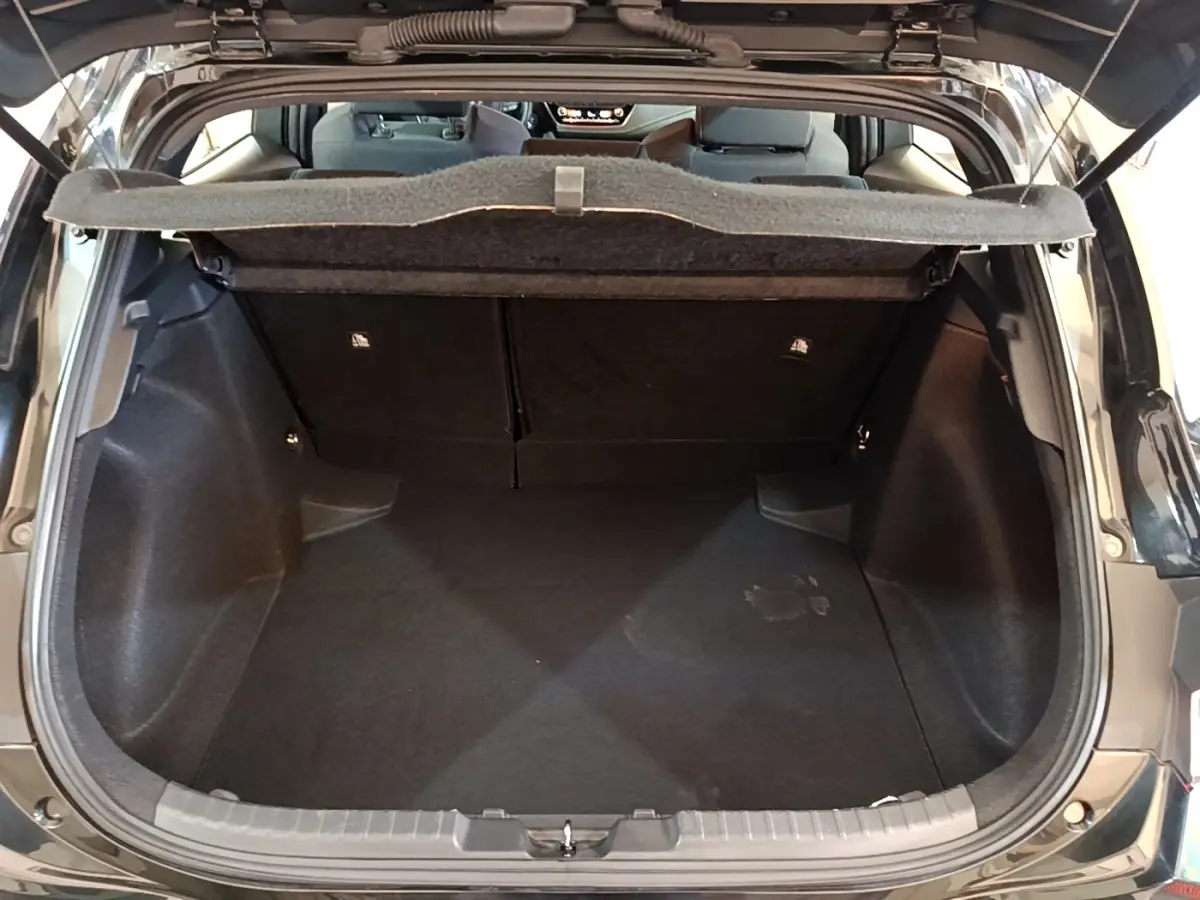 Coffre ouvert d'une Toyota Corolla hybride noire, vue arrière montrant l'espace de chargement et la tablette de séparation.