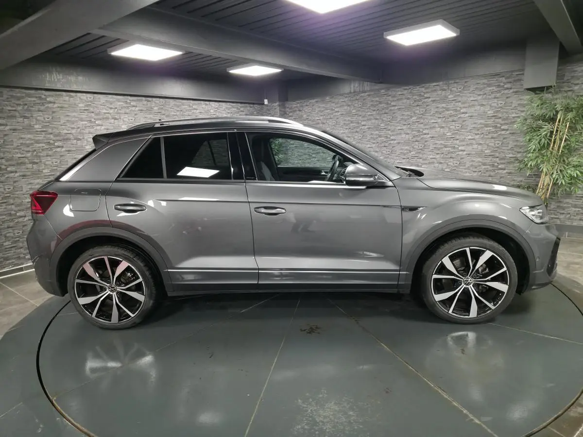 Vue de profil côté gauche d'un Volkswagen T-Roc gris métallisé avec jantes alliage 19 pouces et finitions R-Line.