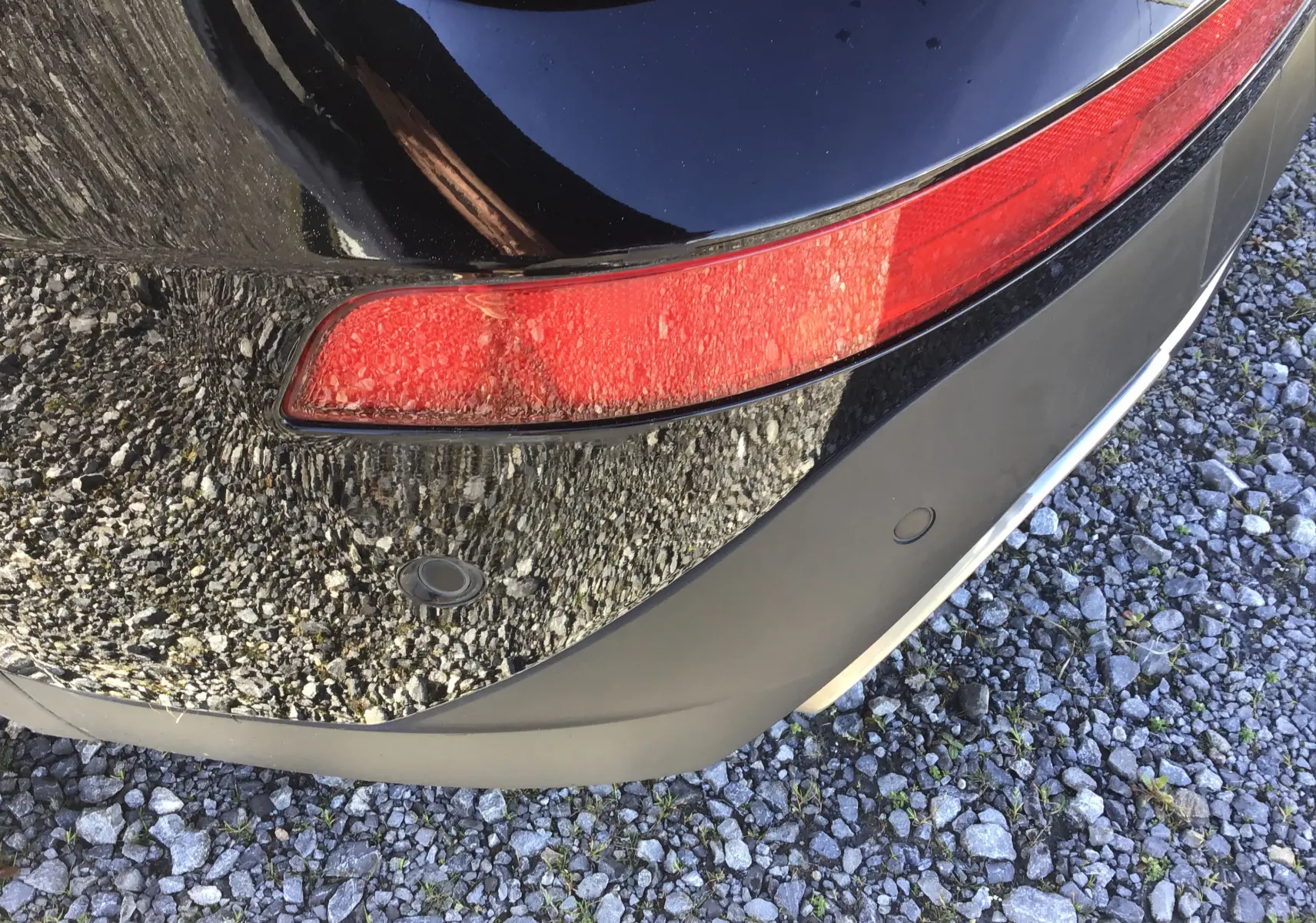 Gros plan sur le feu arrière droit et le pare-chocs noir du DS7 Crossback 2023, avec capteurs de stationnement visibles.