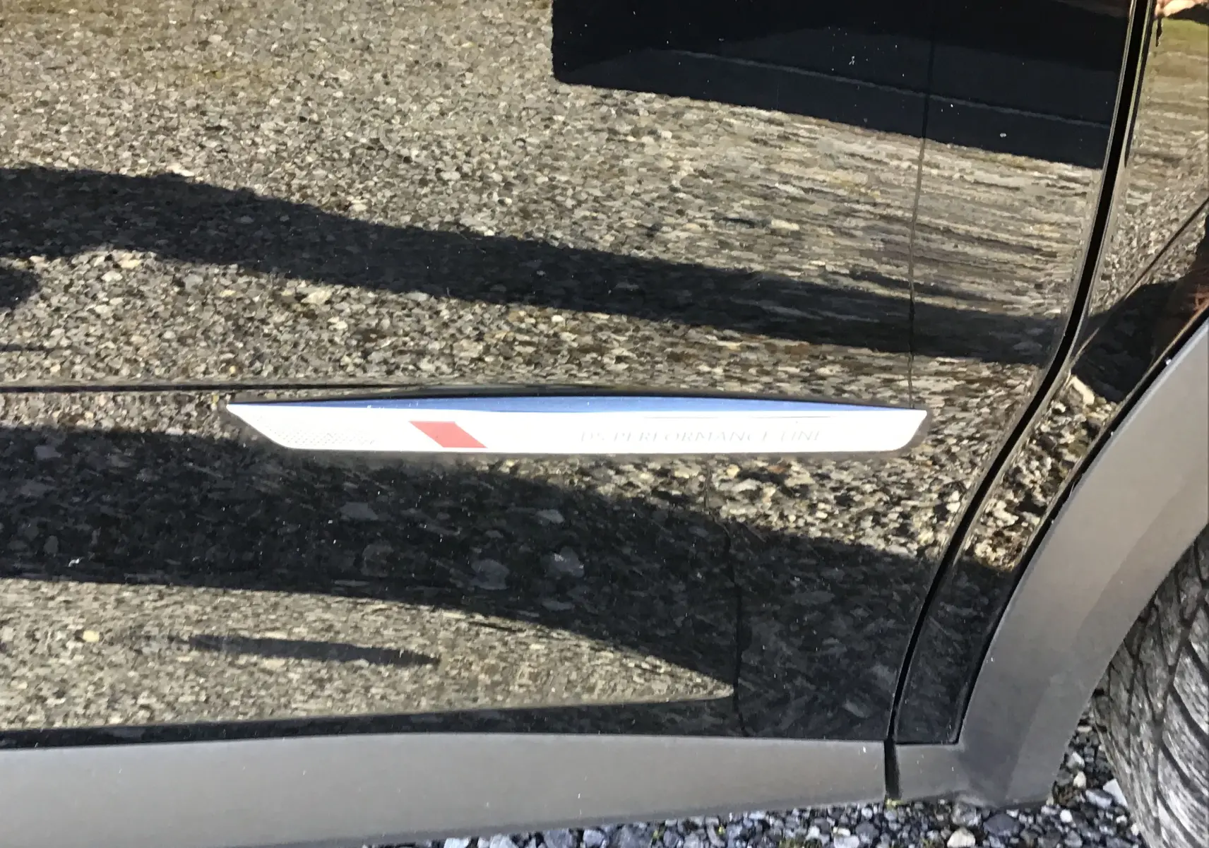 Gros plan sur la porte côté droit d’un DS7 Crossback noir avec l’inscription Performance Line+ visible.