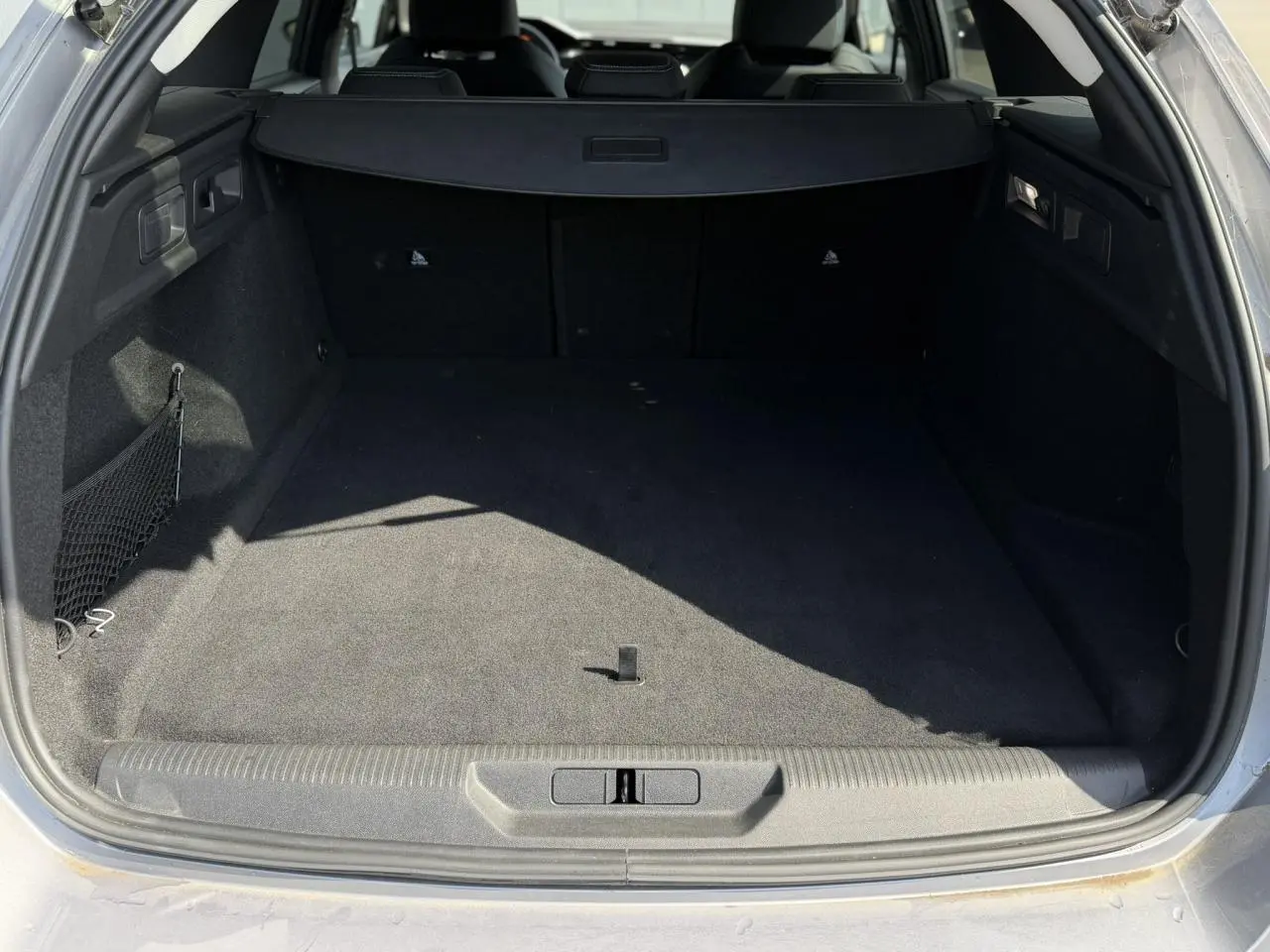 Coffre ouvert d’un Peugeot 308 SW gris Artense, montrant un espace de chargement vide et tapis noir.