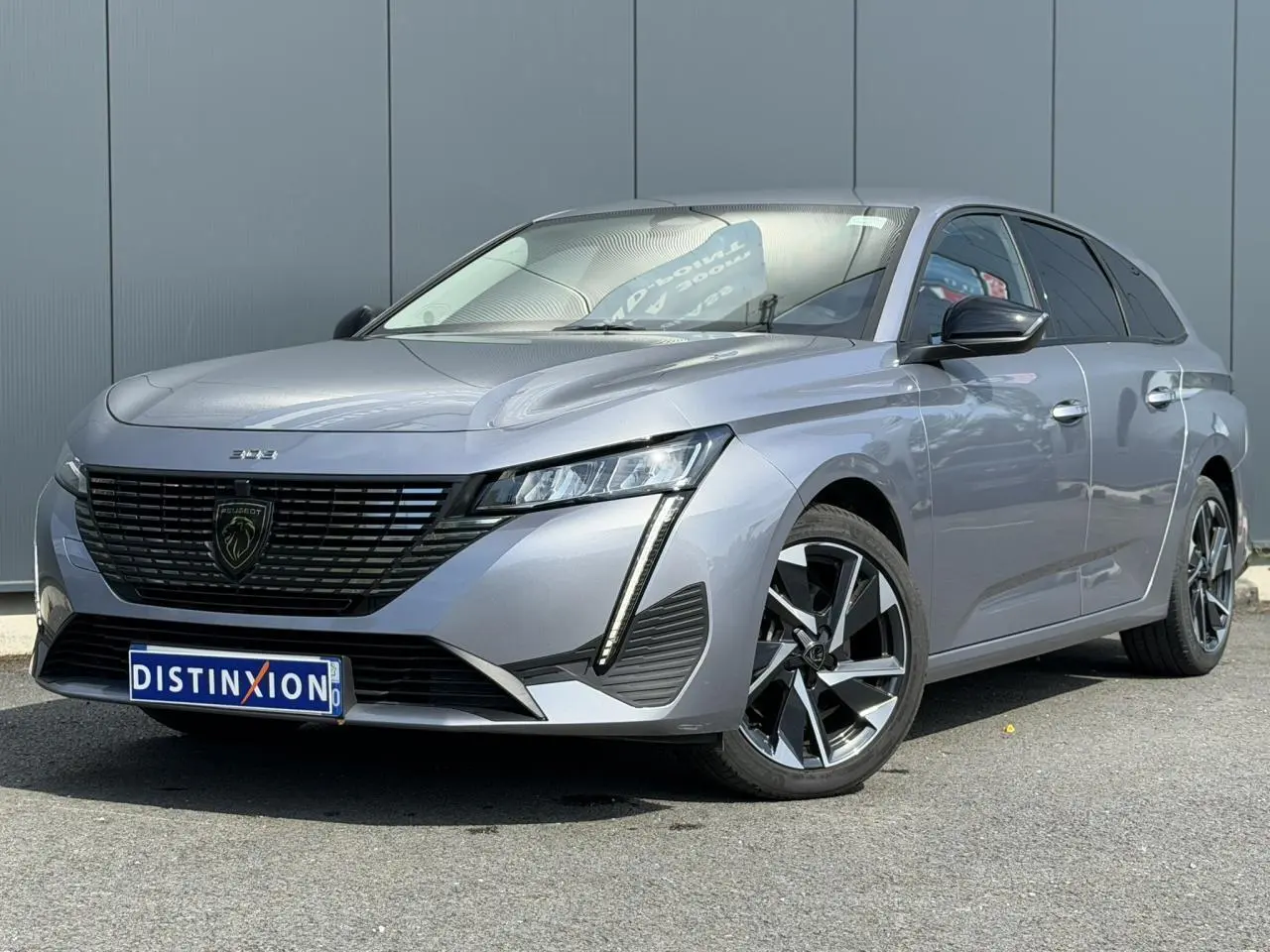 Peugeot 308 SW gris Artense vue 3/4 avant droit, jantes alliage 17'' et calandre noire distinctive.