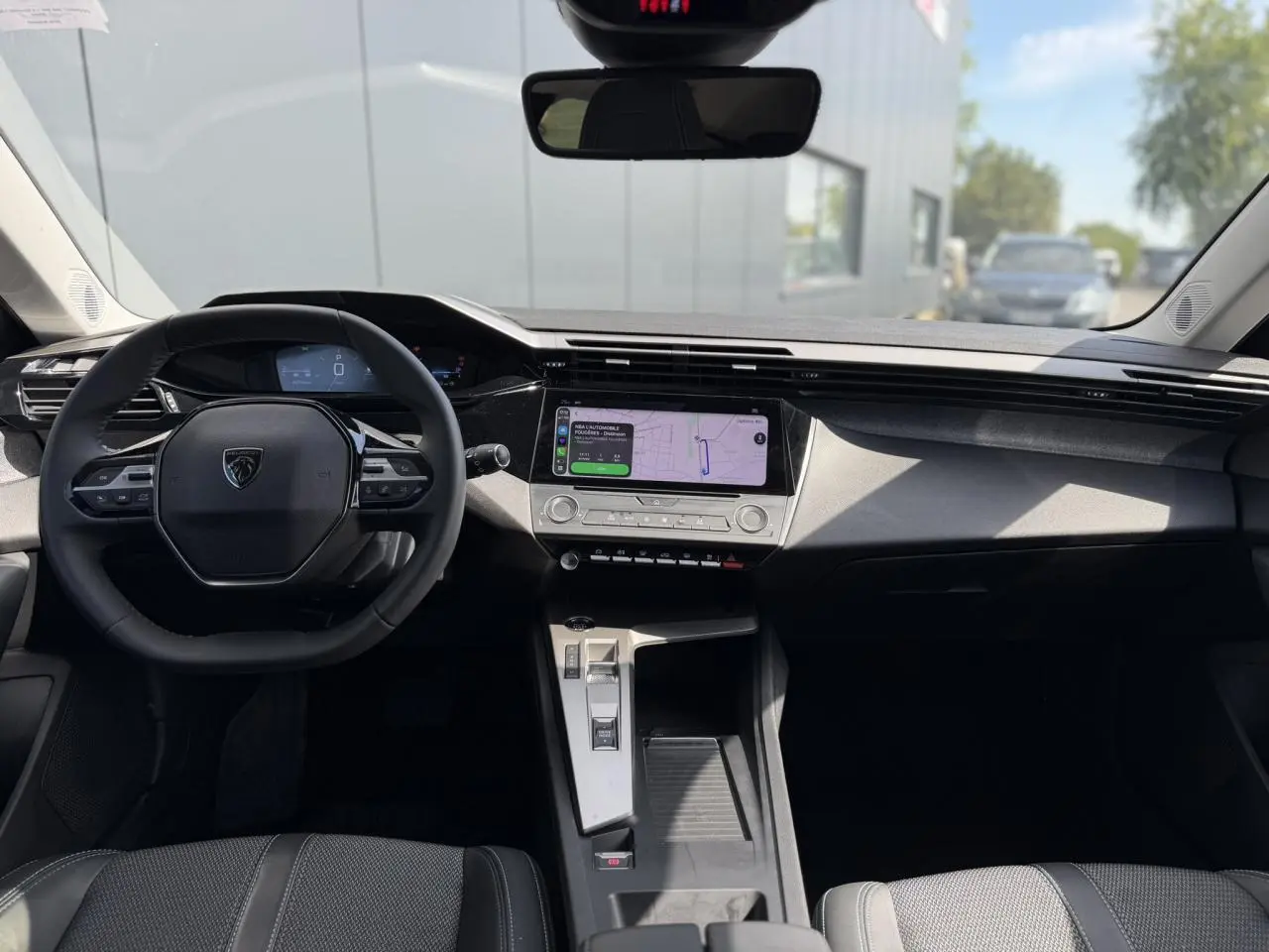 Vue intérieure avant du Peugeot 308 SW 2025 avec tableau de bord noir et écran tactile central lumineux.