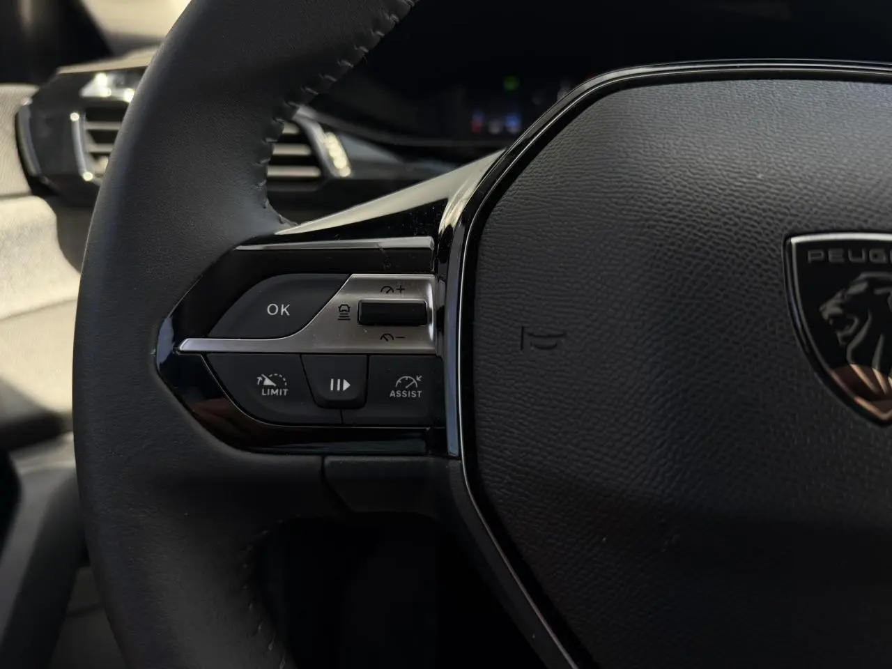 Gros plan sur le volant noir de la Peugeot 308 SW 2025, avec commandes du régulateur adaptatif visibles à gauche.