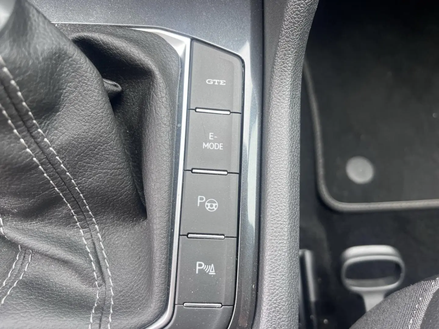 Gros plan sur les boutons de commande du mode GTE et E-MODE dans l’habitacle noir du Volkswagen Tiguan gris dauphin.