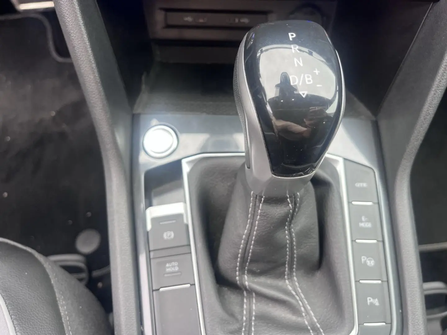 Le levier de vitesse automatique noir du Volkswagen Tiguan 1.4 eHybrid vu en gros plan, entouré de boutons de contrôle.